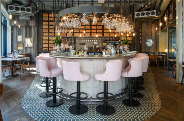 Pink stools lined up around a wine bar